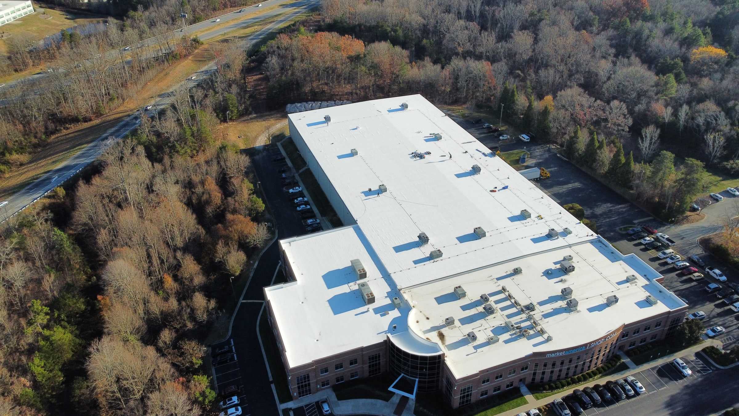 Drone view of a large commercial building with a white flat roof.