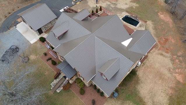 Home from above with a bronze metal roof over the house and garage.