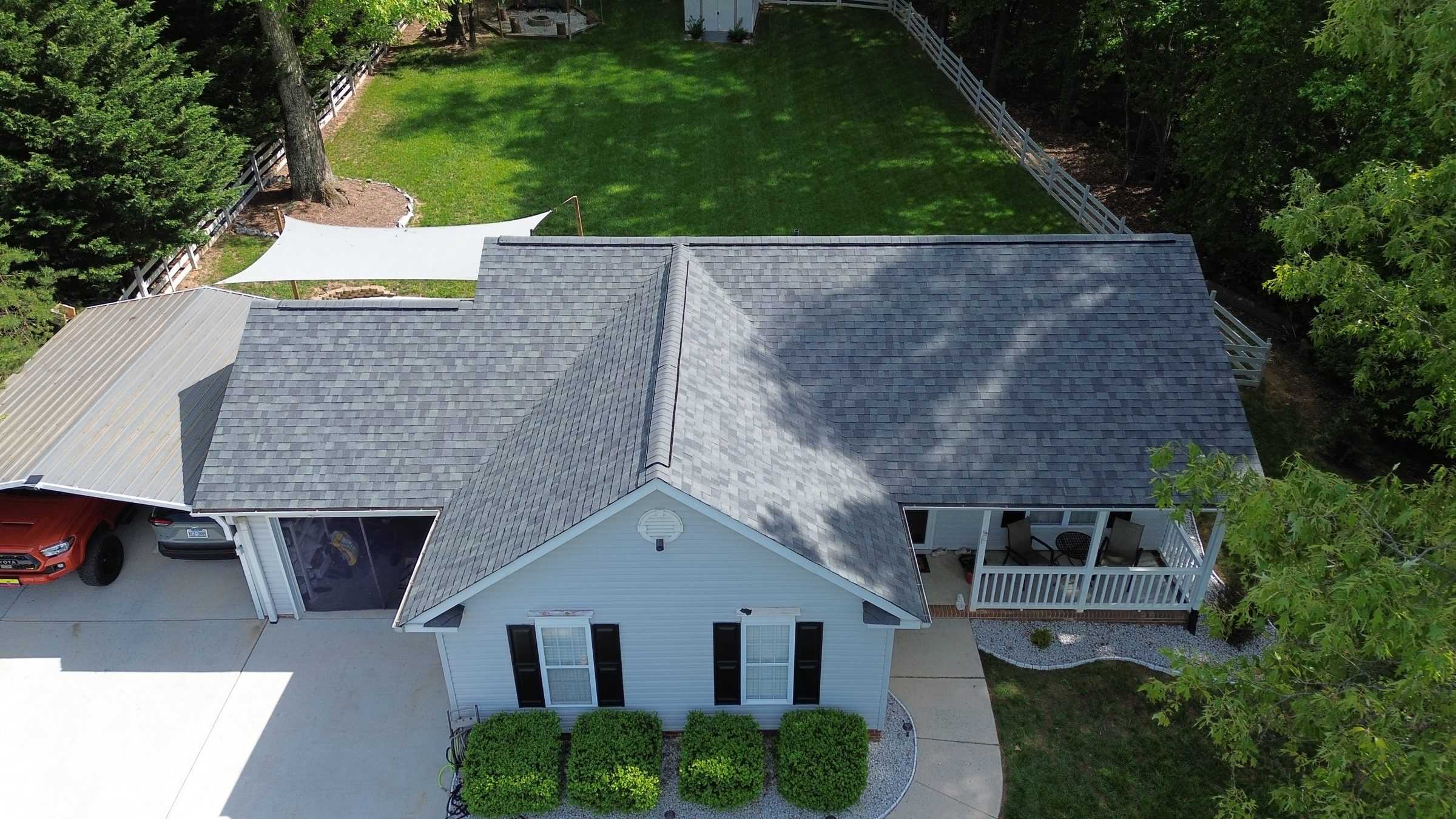 Drone view of a white house with a new light gray shingle roof.