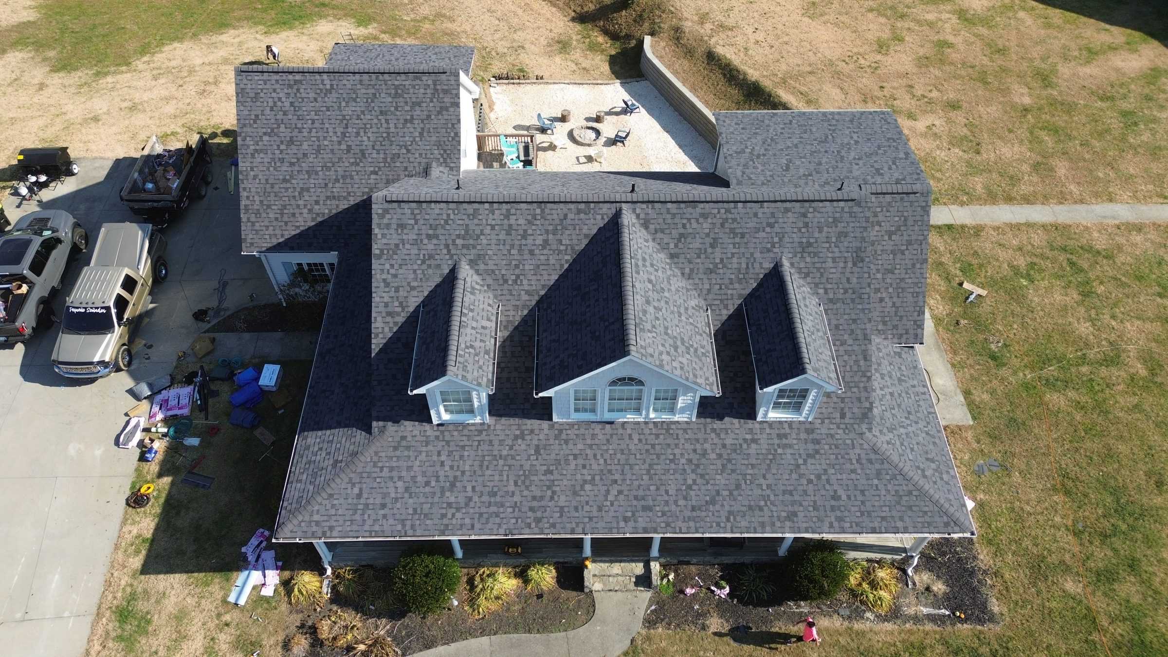 Drone view of a house with three dormers and a new dark gray roof.