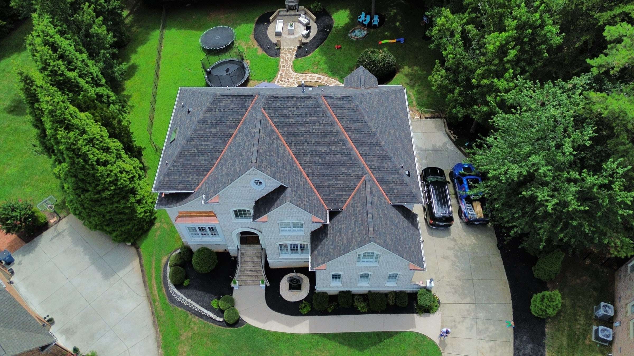 Large home from above with a dark shingle roof and copper-colored accents along the hips.
